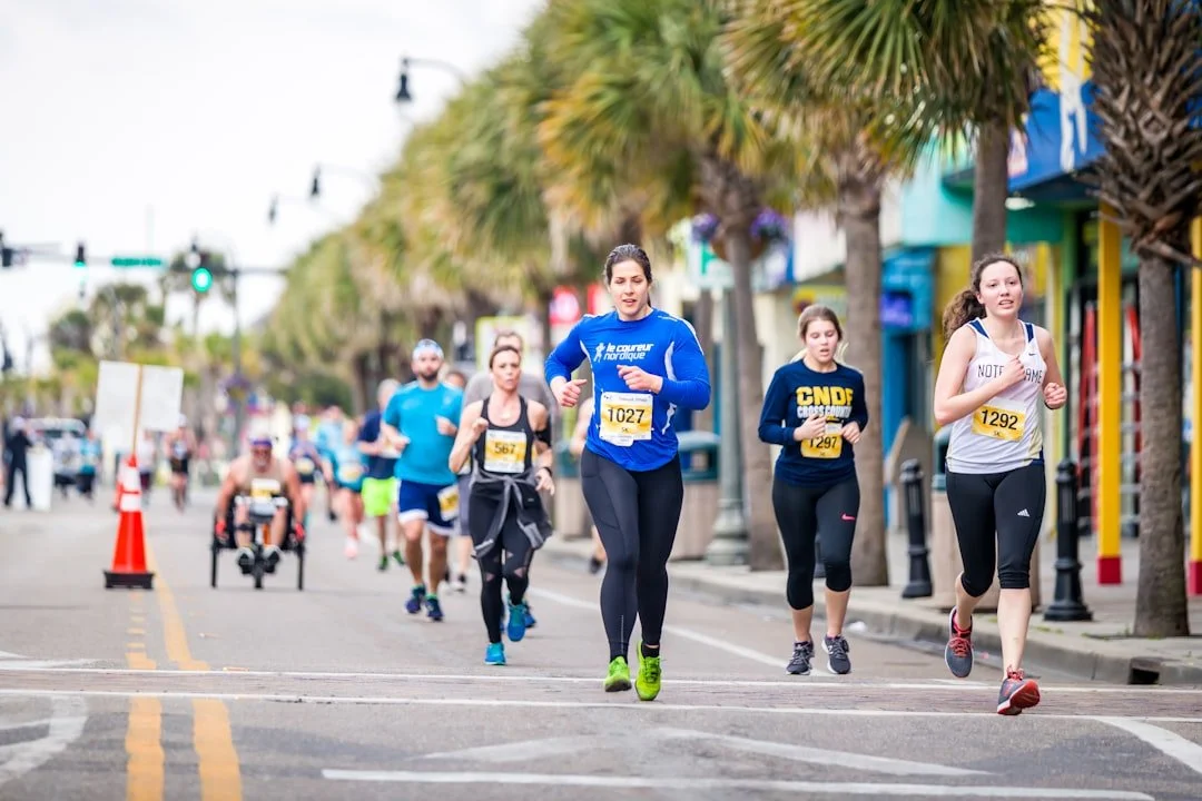 Runners racing down a palm-tree-lined main street